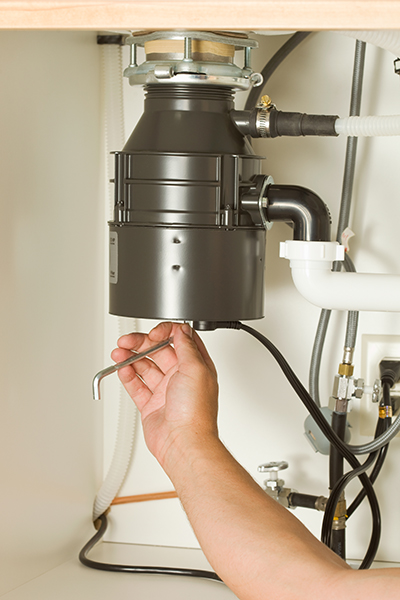 Male Hand Using Wrench on Kitchen Sink Garbage Disposal